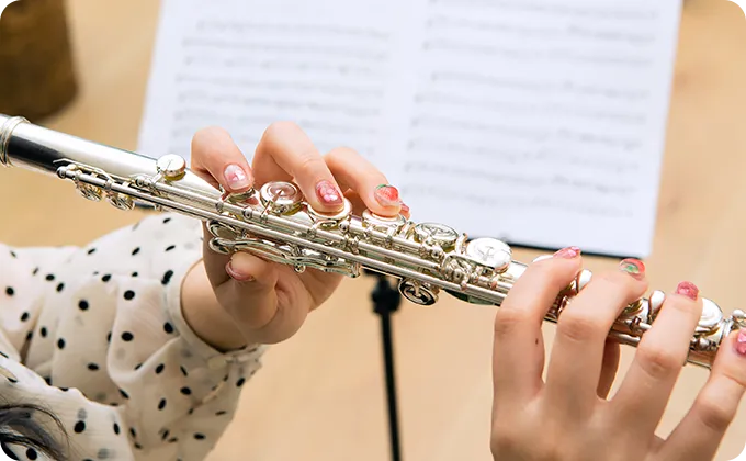 フルートを構える女性の手元のクローズアップで、丁寧にキーを押さえている様子