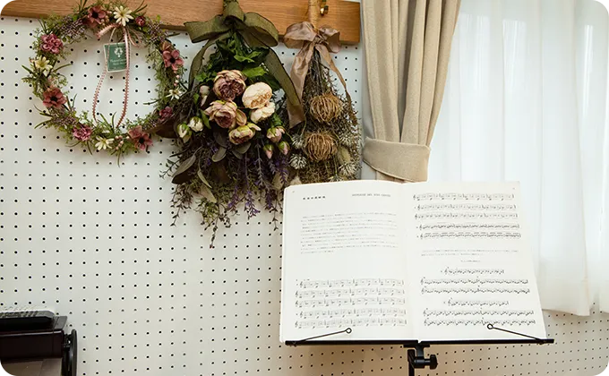 楽譜が開かれた譜面台が室内の壁際に置かれている音楽練習の一場面
